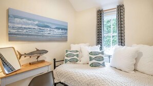 A bedroom with a bed, a desk, a chair, a window with curtains, and a painting of the ocean. - 2 Bed in Llwyngwril (oc-58564) (Llwyngwril)