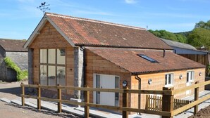 Ein Holzhaus mit geneigtem Dach, einem großen Fenster und einem kleinen Anbau.