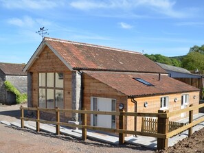 A wooden building with a sloped roof, a large window, and a small attached structure. - 3 Bed in Bristol (oc-58129) (Burrington)