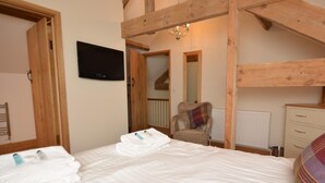 Ein Schlafzimmer mit Bett, Fernseher, Stuhl und Holzbalken.