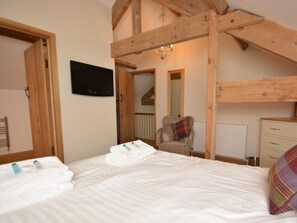 A bedroom with a bed, a television, a chair, and wooden beams. - 3 Bed in Bristol (oc-58129) (Burrington)