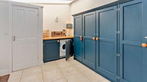 Een kleine keuken met een wasmachine, kastjes en een aanrecht.