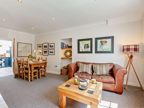 A living room with a brown leather sofa, a wooden coffee table, a dining area with a wooden table and chairs, and framed artwork on the walls. - 2 Bed in Cartmel (oc-lcc47) (Cartmel)