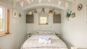 Um quarto com uma cama, uma janela, um relógio e uma estante com objetos decorativos.