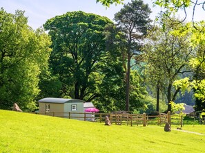 A rustic cabin with a small porch, surrounded by lush greenery and trees. - 1 Bed in Macclesfield (oc-58462) (Wincle)