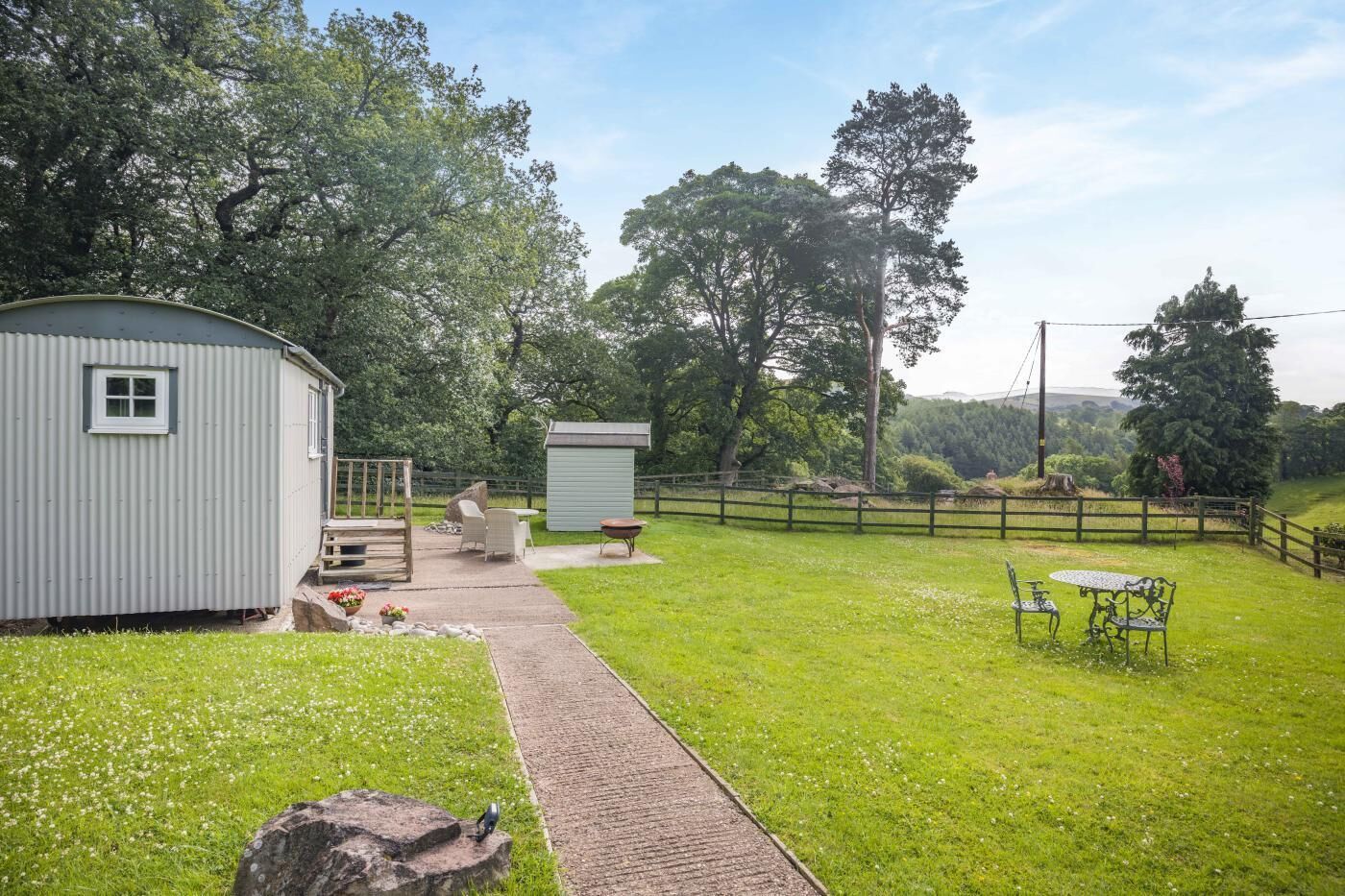 Un espacio exterior cercado con un patio, un cobertizo y una pequeña construcción.