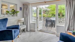 Ein Zimmer mit Oberlicht, einem Essbereich mit Tisch und Stühlen sowie einem blauen Sessel.