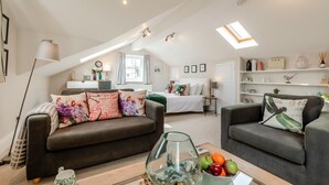 Ein geräumiger Lofts mit hoher Decke, einem Schlafsofa, einem Essbereich und einer Küchenzeile.