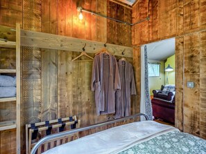 A wooden room with a bed, a hanging robe rack, and a mirror reflecting another room. - 1 Bed in St. Austell (oc-58376) (Pentewan Valley)