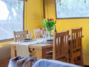 A dining table with chairs, a vase of flowers, and wine glasses set for a meal. - 1 Bed in St. Austell (oc-58376) (Pentewan Valley)