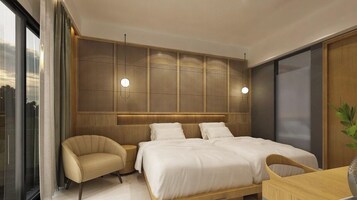 Un dormitorio moderno con una cama grande, dos mesitas de noche, una silla y vistas a la ciudad.