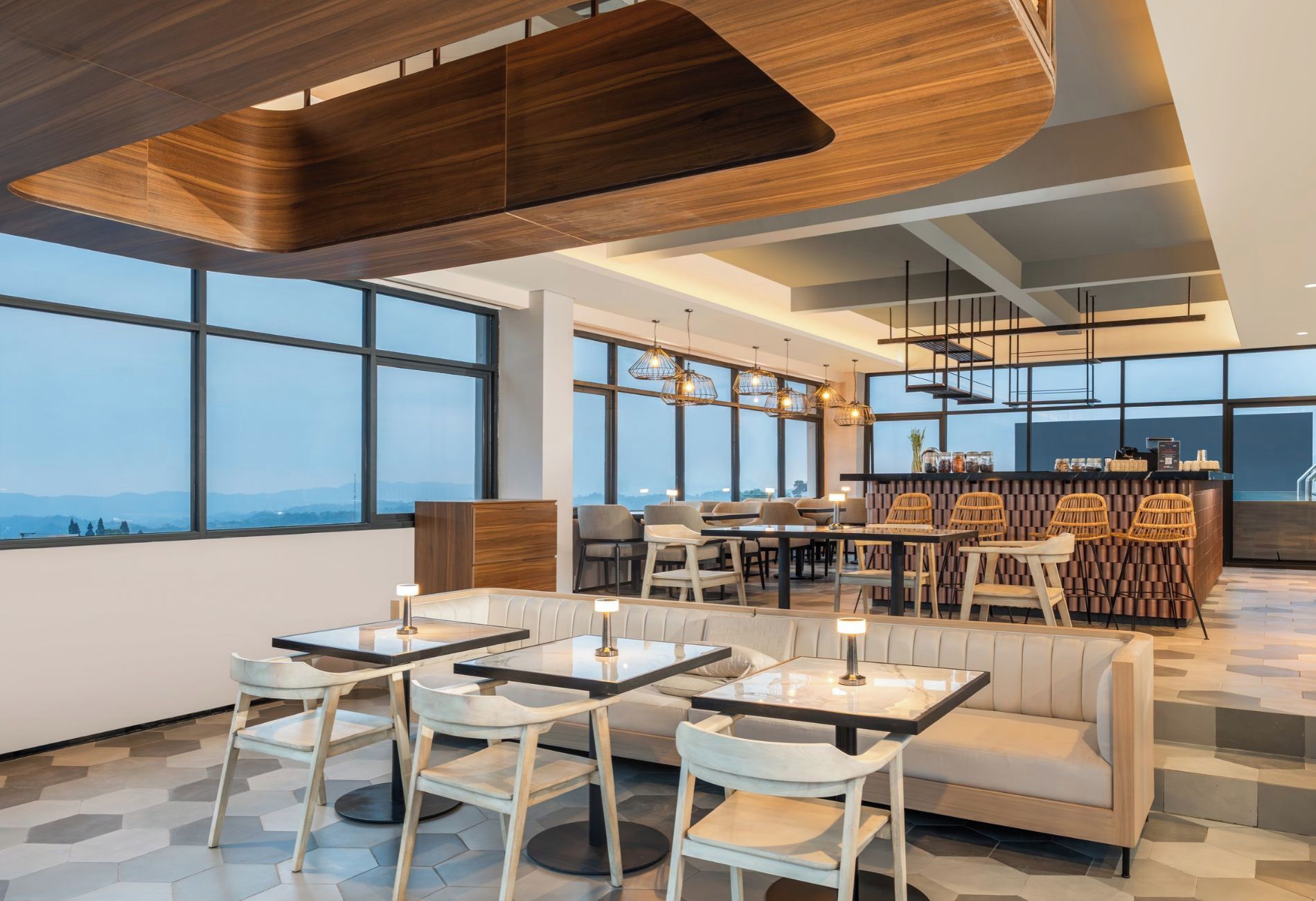 Un intérieur moderne avec un bar, des espaces de détente et de grandes fenêtres offrant une vue panoramique.