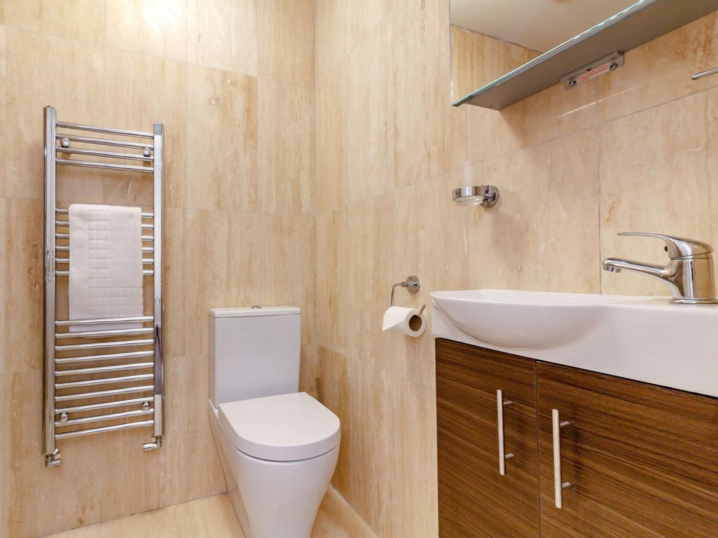 Un baño moderno con inodoro, toallero, lavamanos y ducha.