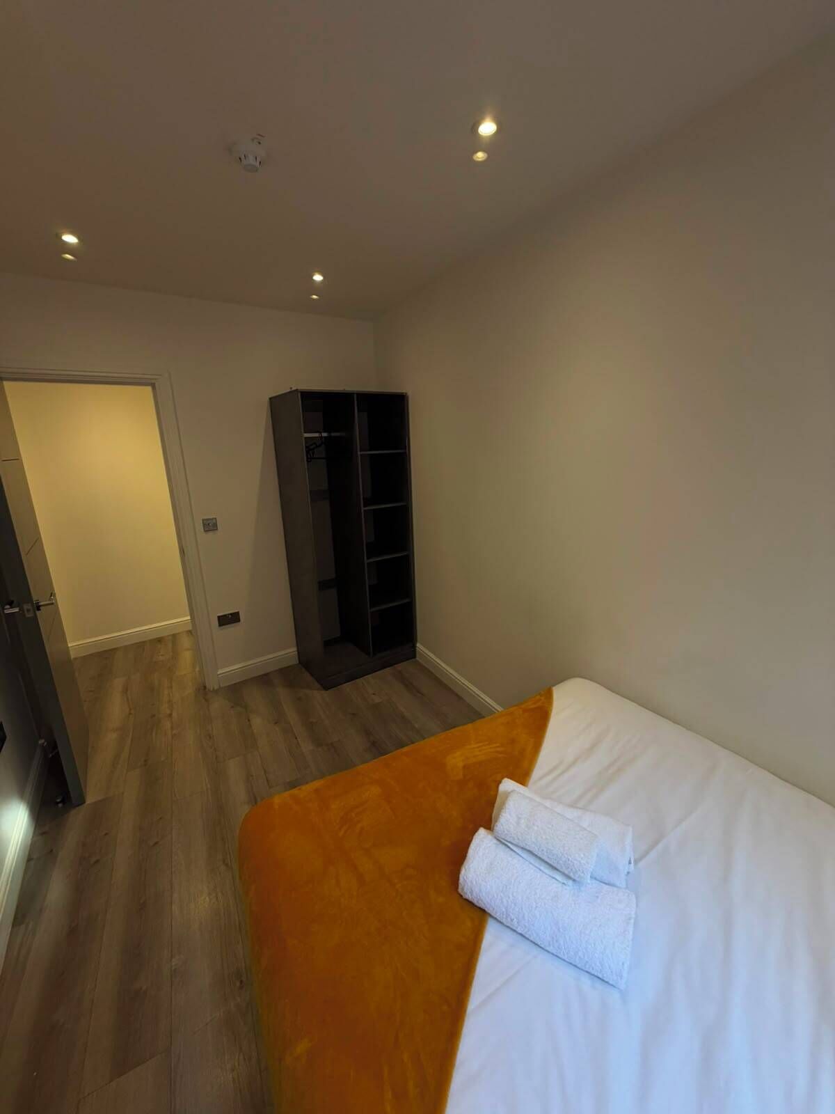 Ein Schlafzimmer mit Bett, Schrank und einer Tür zu einem anderen Raum.