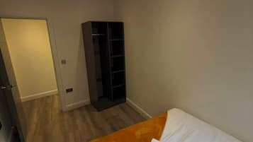 Ein Schlafzimmer mit Bett, Schrank und einer Tür zu einem anderen Raum.