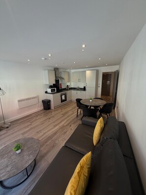 A modern living room with a sofa, a round coffee table, and a dining area with a table and chairs. - Dale Street Apartments by StaySavvy (Liverpool)