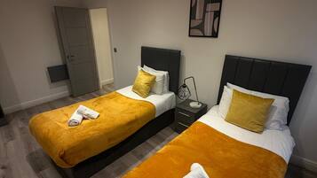 Ein Hotelzimmer mit zwei Betten, jeweils mit Kopfstütze, Nachttisch und einem Wandbild.