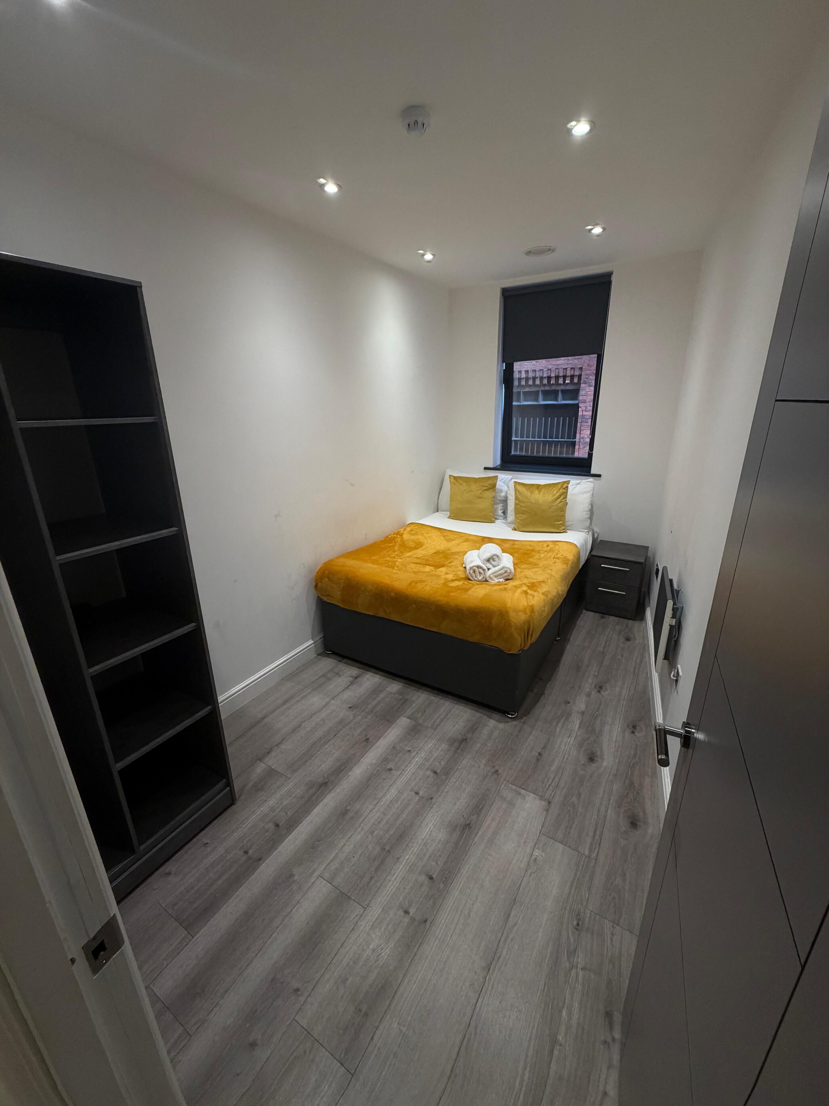 Ein Schlafzimmer mit Bett, Kleiderschrank, Nachttisch und einem Fenster mit Blick.
