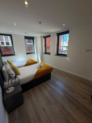 A modern bedroom with a large bed, two windows, and a wooden floor. - Dale Street Apartments by StaySavvy (Liverpool)