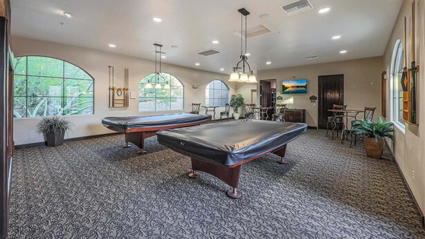 A pool table in a room with large windows, a dining area, and a view of the outdoors. - Villa Grand 2 Bedroom Condo (Phoenix)