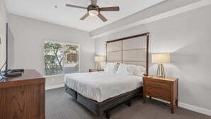 A bedroom with a bed, bedside tables, a ceiling fan, and a window with blinds. - Villa Grand 2 Bedroom Condo (Phoenix)
