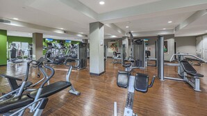 A gym with various exercise machines, a central pillar, and a green wall. - Villa Grand 2 Bedroom Condo (Phoenix)
