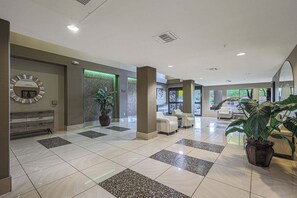 A spacious lobby with a reception desk, seating area, and potted plants. - Villa Grand 2 Bedroom Condo (Phoenix)