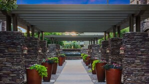 A covered walkway with stone walls and potted plants, leading to a central fountain. - Villa Grand 2 Bedroom Condo (Phoenix)