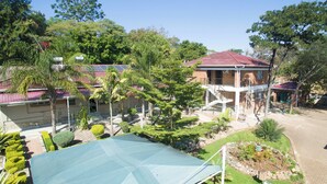 A residential area with a house featuring a red roof, a covered outdoor area, and a small garden.
