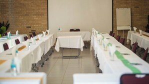 A conference room with tables set up for a meeting, a projector screen, and a whiteboard.