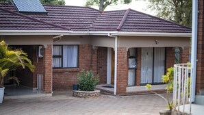 A residential building with a covered porch, brick walls, and a tiled roof.