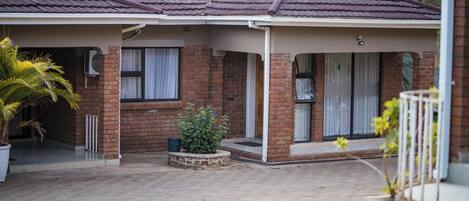 A residential building with a covered porch, brick walls, and a tiled roof.