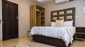 A bedroom with a bed, a wardrobe, a headboard, and a built-in shelf unit.