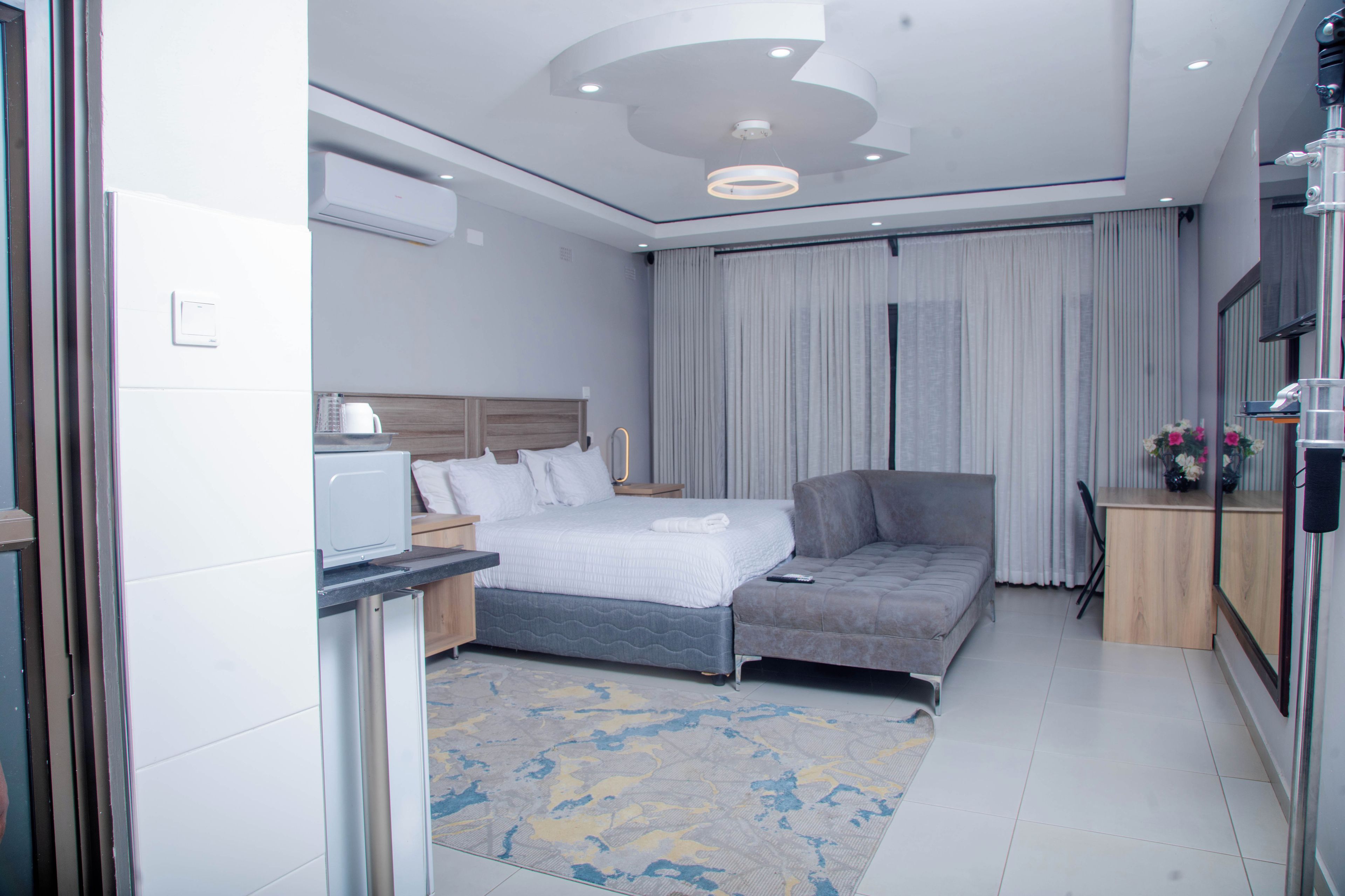Habitación de hotel moderna con cama, sofá, escritorio con computadora y televisor.