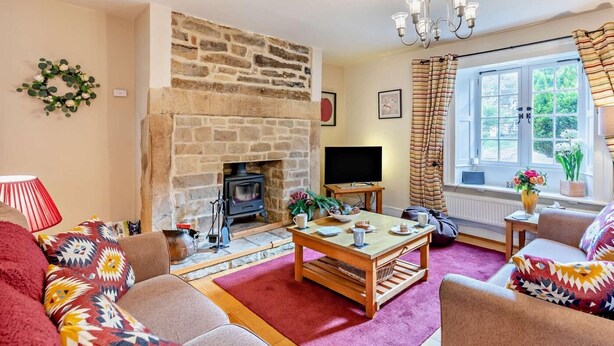 A cozy living room with a stone fireplace, a television, and a comfortable seating area. - 3 Bed in Backworth (oc-cn013) (Backworth)