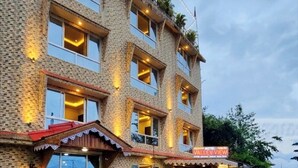 A multi-story building with a stone facade, multiple balconies, and a sign indicating a restaurant.