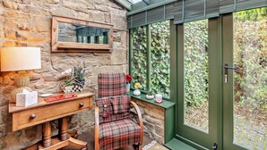 A cozy room with a stone wall, a wooden desk, a plaid chair, and a green door with a window. - 3 Bed in Backworth (oc-cn011) (Backworth)