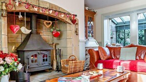 A cozy living room with a stone fireplace, a leather sofa, and a wooden coffee table. - 3 Bed in Backworth (oc-cn011) (Backworth)