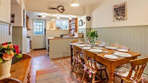 A dining area with a wooden table set for four, surrounded by wooden chairs with red and white checkered seat covers. - 3 Bed in Backworth (oc-cn011) (Backworth)