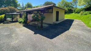 A single-story building with a covered patio area, a garage, and a driveway. - Holiday Home 'Villa Moutiques' with Private Terrace, Private Garden and Wi-Fi (Cazaubon)
