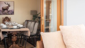 A dining area with a table set for four, a sofa with a cushion, and a painting of an elk on the wall. - 5 Bed in Aberystwyth (oc-58889) (Llanrhystyd)