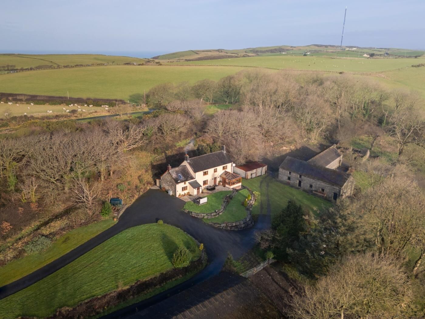 A rural property with a main house, a smaller adjacent building, and a fenced yard.