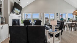 Amplia sala de estar con televisor, asientos y ventanas grandes.