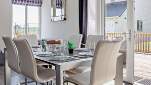 Un comedor con una mesa preparada para cuatro, sillas, un pastel y una ventana con cortinas.