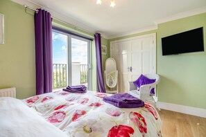 A bedroom with a bed, a wardrobe, a television, and a balcony with curtains. - 3 Bed in Morpeth (oc-cn027) (Low Hauxley)