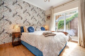 A bedroom with a large bed, a nightstand, a lamp, and a view of the outside. - 3 Bed in Morpeth (oc-cn027) (Low Hauxley)