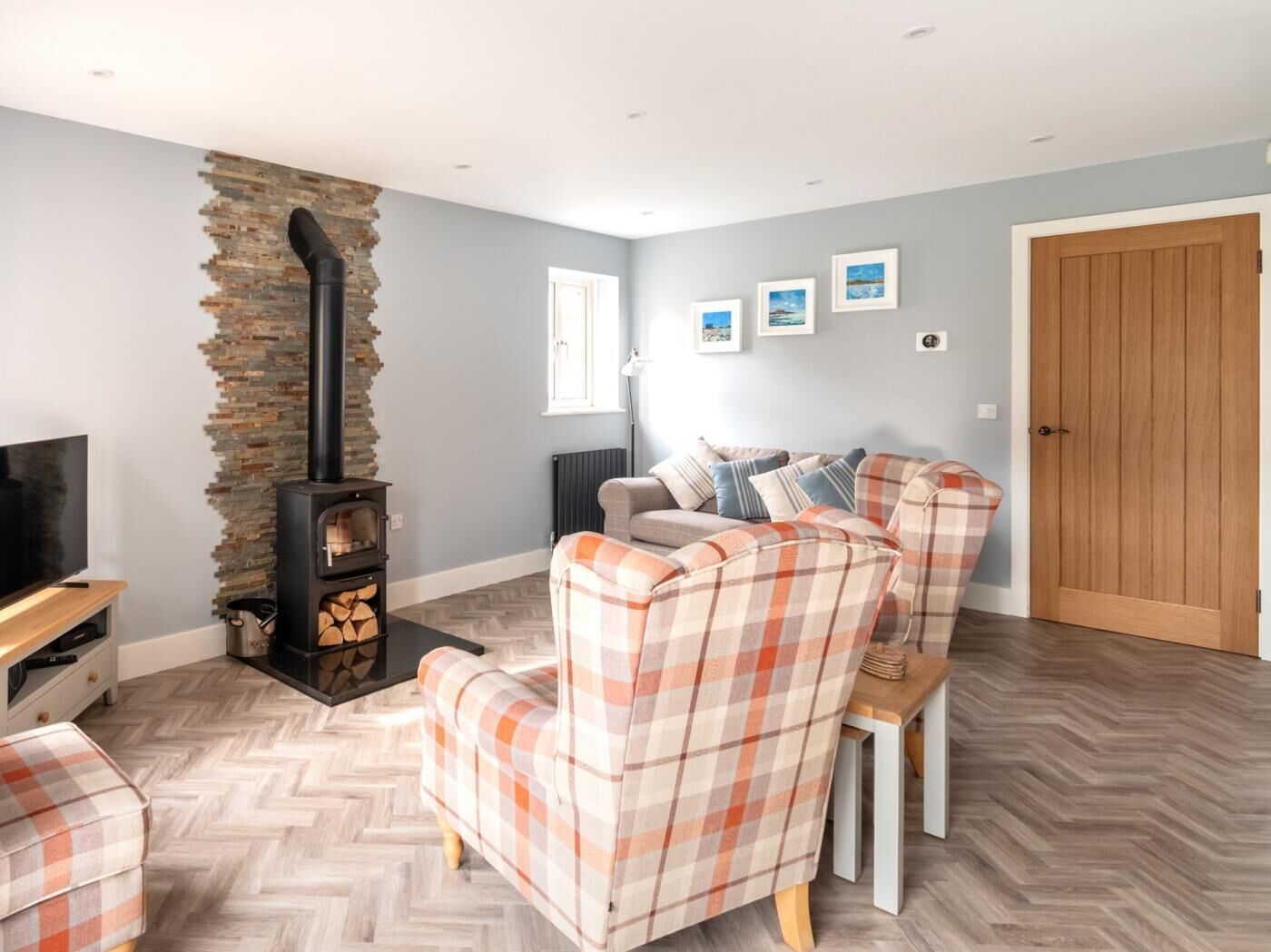 A living room with a fireplace, a sofa, a television, and a herringbone floor pattern.