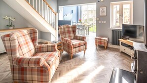 A living room with a herringbone floor, a staircase, a dining area, and a TV. - 2 Bed in Beadnell (oc-cn005) (Beadnell)