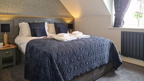 A bedroom with a bed, bedside tables, a window with curtains, and a radiator. - 2 Bed in Beadnell (oc-cn005) (Beadnell)