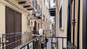 Una calle estrecha flanqueada por edificios, una bicicleta estacionada a la derecha y un objeto decorativo blanco sobre la barandilla.